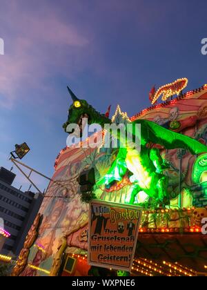 HAMBURG - March 27, 2017: Spooky Horned Green Dragon with yellow glowing eyes - Ghost Train Puppet/Animatronic on German Funfair Hamburger Dom Stock Photo