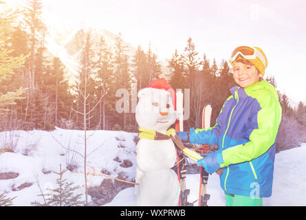 Boy put on scarf making snowman with Santa hat Stock Photo