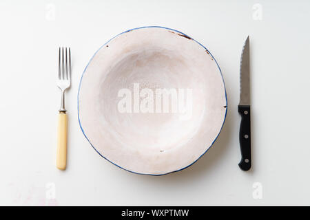 Handmade ceramic empty plate with knife and fork on white background Stock Photo
