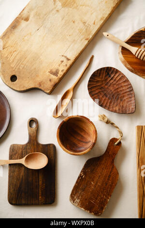Various wooden tableware. Cutting boards, spoons of different forms, plate and bowl on linen tablecloth Stock Photo
