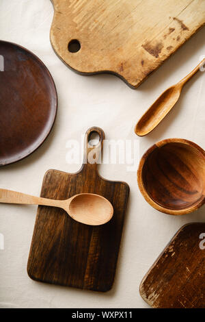 Various wooden tableware. Cutting boards, spoons of different forms, plate and bowl on linen tablecloth Stock Photo
