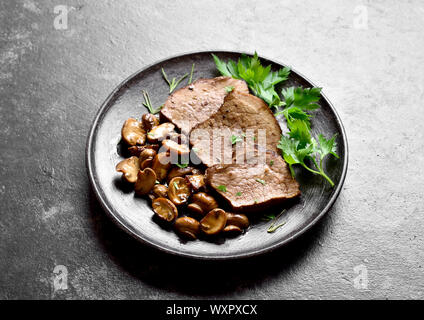 Slow cooked beef with mushrooms on dark stone background. Tasty stewed meat with mushrooms. Close up view Stock Photo