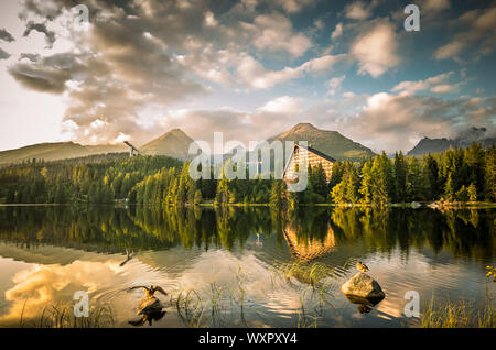 Sunset over Strbske pleso - tarn in High Tatras national park, Slovakia. There are trees and chalet reflections in the lake Stock Photo