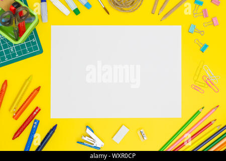 Back to school concept. School supplies. Blank paper page mockup on yellow table background with office tools. Copy space. Flat lay. Stock Photo