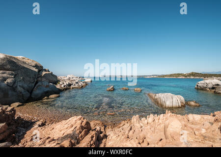 Large granite boulders on the coast of Cavallo Island n the Lavezzi archipelago of Corsica with white cliffs of Bonifacio in the distance Stock Photo