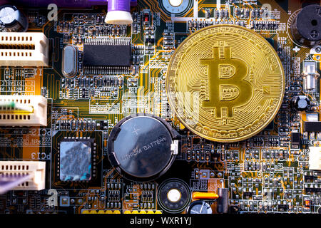 Virtual cryptocurrency money Bitcoin golden coin on a computer printed circuit board PCB. The future of money. Computational equipment. Shot directly Stock Photo