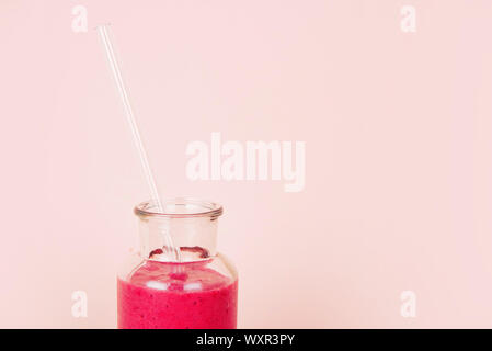 Minimalist composition of glass with raspberry smoothie and with reusable glass straw on pink background Stock Photo