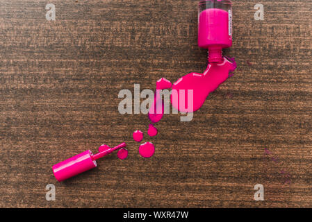 spilled pink nail polish on a wooden background. Drops of nuclear pink varnish on a wooden board Stock Photo
