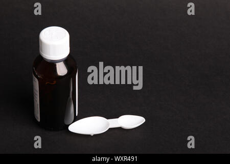 Medical dosage spoon with medicine bottle for oral usage on black background with copy space Stock Photo