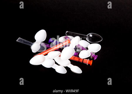 A collection of medical dosage spoons and oral dosage syringes on black background WOP Stock Photo