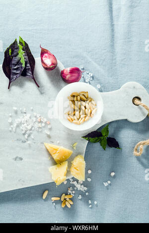 marble cutting board and spices on a linen blue tablecloth. olive oil, pine nuts and basil. copy space Stock Photo
