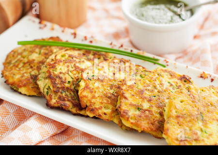 Homemade zucchini patties with herbs, served with pesto. Healthy lunch Stock Photo