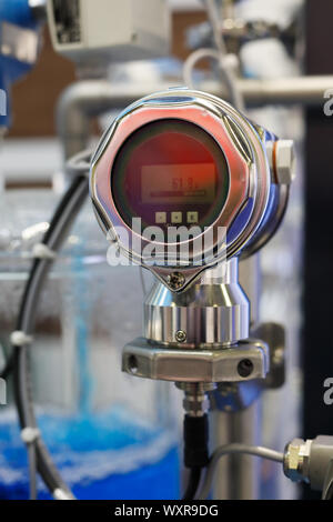 Industrial digital gauge measuring liquid flow at a chemical plant. Selective focus. Stock Photo