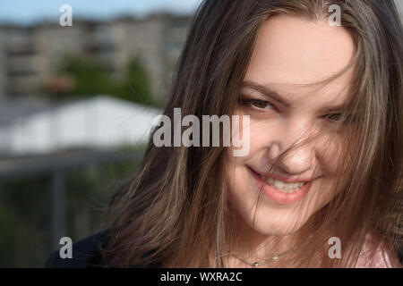 Portrait of brunette girl. Girl in black jacket with long hair on the street in summer day. Plus size model Stock Photo