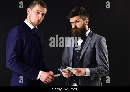 Meeting of reputable businessmen, black background. Man with beard on serious face counting money, pay to partner. Business payment concept. Businessm Stock Photo