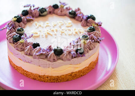 Close image of layer cake with purple cream and blueberries saying happy birthday Stock Photo