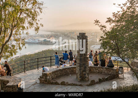 Tourists at viewpoint Gibralfaro overlooking port of Malaga en city, at sunset, Andalusia, Spain. Stock Photo