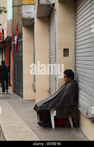 LIMA, PERU - JULY 21, 2013: Unidentified person sitting in front of a closed shop on July 21, 2013 in Miraflores, Lima, Peru. Stock Photo