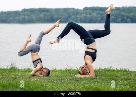 woman and child training near the lake on the grass, outdoor sports, healthy sport lifestyle, fitness, yoga Stock Photo