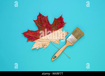 Brush and maple leaf on a blue background. Autumn concept, flat lay. Top view. Stock Photo