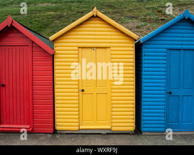 Yellow beach hut between an red and blue beach hut, Whitby. Stock Photo