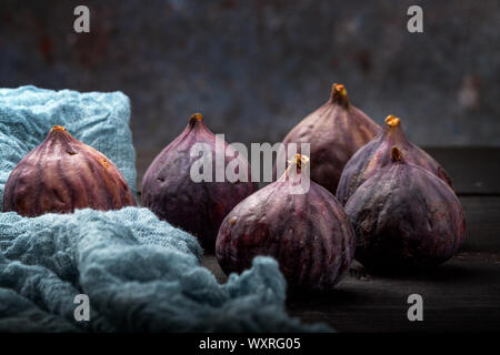 Fresh figs lie on a black wooden table. Beautiful blue fig fruits close up Stock Photo