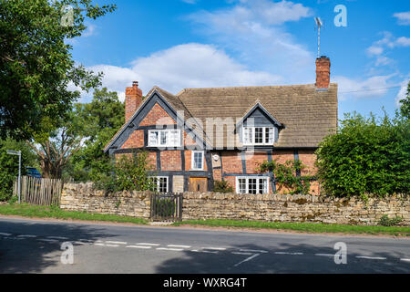 Timber framed red brick cottage and front garden. Great Washbourne, Cotswolds, Wychavon district, Worcestershire, UK Stock Photo