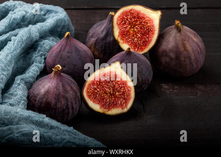 Fresh figs lie on a black wooden table. Beautiful blue fig fruits close up Stock Photo