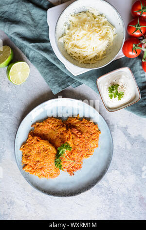 Homemade fried sweet potato cakes on a plate served with sour cream dip Stock Photo