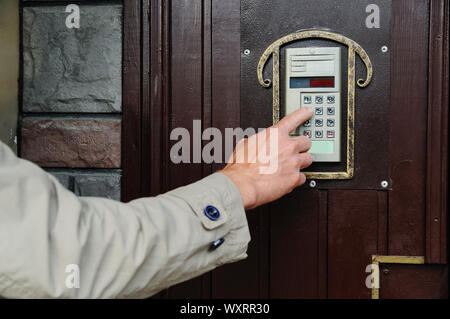 Man's hand is dialing the code on the door intercom of the front door. Stock Photo