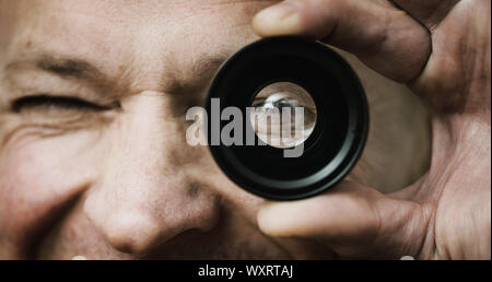 The man is holding and looking through the photo lens. Stock Photo