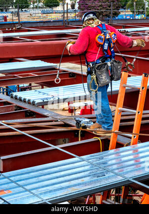 Cypress, CA / USA - Sept. 16, 2019: Construction worker wearing hardhat is working high up on the scaffolding of a building site. Stock Photo