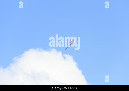 Stunning view of a private white jet flying in a blue and cloudy sky. Business jets is a jet plane used to transport groups of businessmen. Stock Photo