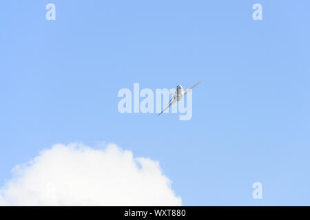 Stunning view of a private white jet flying in a blue and cloudy sky. Business jets is a jet plane used to transport groups of businessmen. Stock Photo