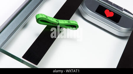 sliver bathroom scale with green measuring tape on white background.  Health and weight loss Concept Stock Photo