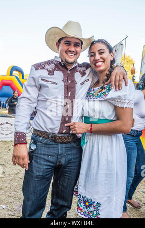 A Hispanic couple at the Mercado del Norte, part of the fiesta in Santa Barbara, California. They smile as he holds his arm around her and both of the Stock Photo