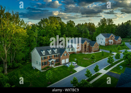 American luxury real estate single family houses with brick facade and two car garages in a new construction Maryland street neighborhood USA aerial Stock Photo