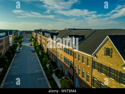 American real estate neighborhood street in Maryland with typical east coast brick facade townhouses with blue cloudy sky aerial view Stock Photo