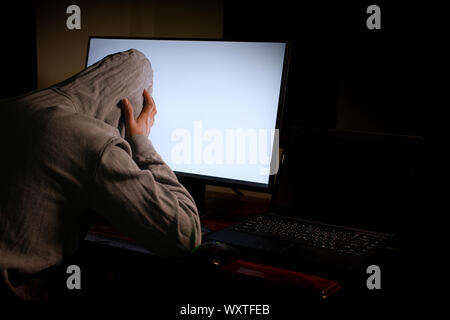 Women hacker breaks into government data servers and Infects Their System with a Virus at his hideout place has dark blue atmosphere,  Lady hooded usi Stock Photo