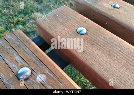 Close-up of wooden boards fastened with metal nails on a bench outdoors. Stock Photo