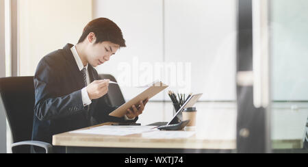Young handsome accountant working on his reports while checking the document in the office room Stock Photo