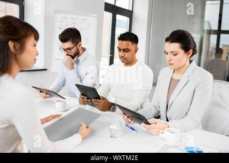 new job, hiring and employment concept - international team of recruiters with tablet computers having interview with female employee at office Stock Photo