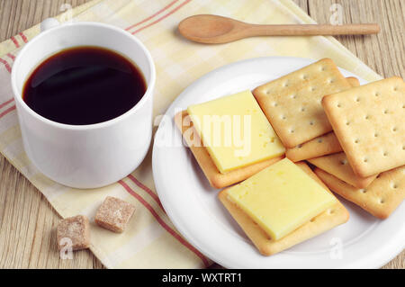 Cup of coffee and delicious cracker cookies with cheese and on table Stock Photo