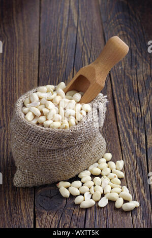 Peanuts in sack with scoop on dark wooden background Stock Photo