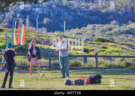Actors Jake Ryan, Sam Frost and a member of the crew prepare to film an outdoor scene of Home & Away tv series at Palm Beach, Australia Stock Photo