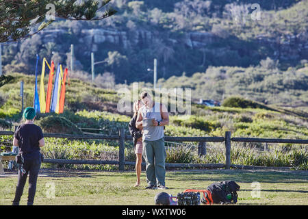 Actors Jake Ryan, Sam Frost and a member of the crew prepare to film an outdoor scene of Home & Away tv series at Palm Beach, Australia Stock Photo
