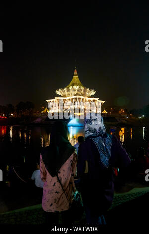 People gather at night to watch the water fountain and laser light show in front of the Legislative Sarawak State Assembly building.  In Kuching, Sara Stock Photo