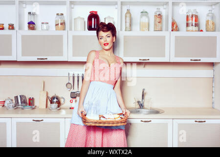 Woman in the kitchen is preparing cakes. She is a retro housewife style. Stock Photo