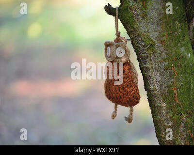 Hand knitted owl hanging on a tree Stock Photo