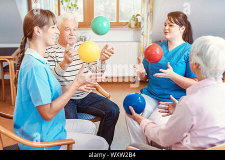 Group of seniors doing sport and gymnastics with balls in the pensioners home Stock Photo